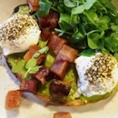 Avocado hummus toast with poached eggs & candied bacon.