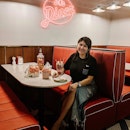Welcome to the '60s ~ Oh, oh, oh 🎶 Have a milkshake in this charming American-style diner, complete with upholstered booths, Silestone table, ceramic mosaic flooring, and bright neon lights.