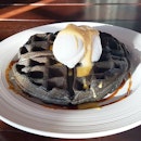 Charcoal waffle serve with vanilla ice-cream, drizzle with salted egg yolk sauce.