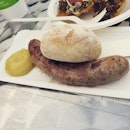 Some bratwurst with a sourdough bread and mustard on the side.